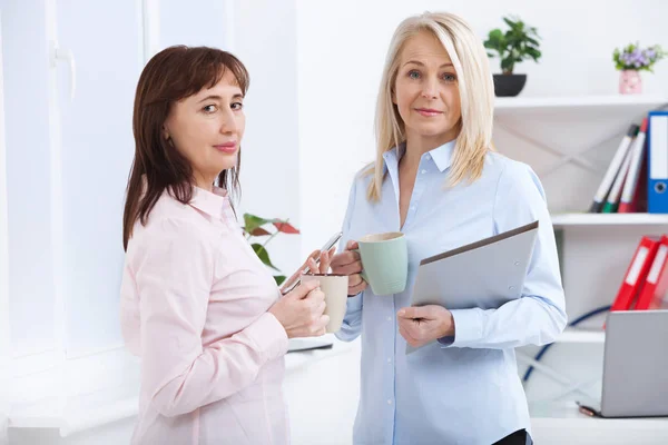 Office kaffepaus. Två kvinnliga kollegor med koppar kaffe prata. — Stockfoto