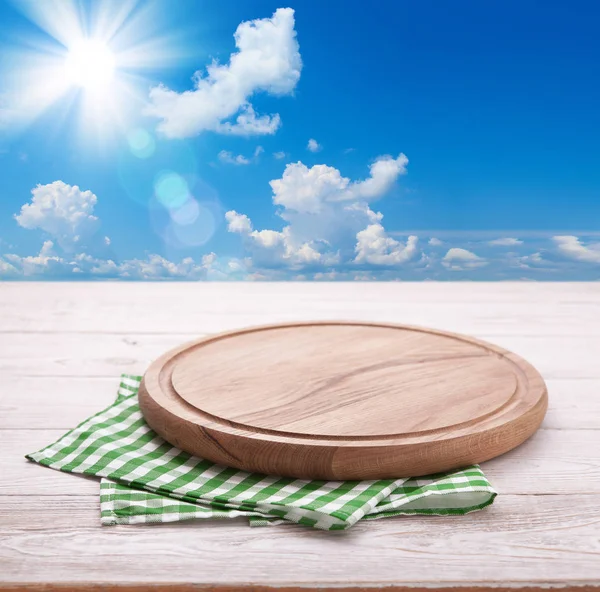 Wooden deck table with tablecloth over summer sky and sun background — Stock Photo, Image