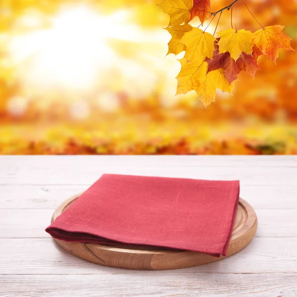 Pizza board with towel on wooden desk. Autumn background. Top view mock up. Selective focus.