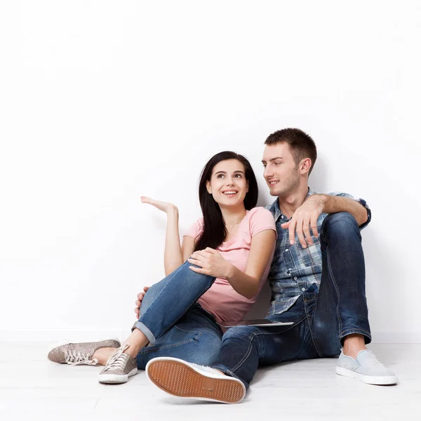 Feliz joven pareja sentada en el suelo mirando hacia arriba mientras sueña con su nueva casa y mobiliario. Prepárate. —  Fotos de Stock
