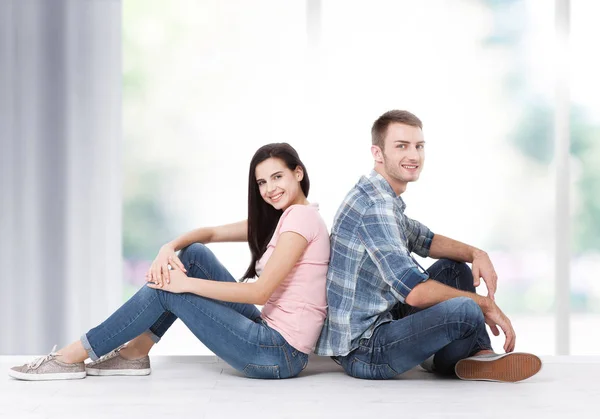 Joyeux jeune couple assis sur le sol regardant vers le haut tout en rêvant de leur nouvelle maison et d'ameublement. Maquette — Photo