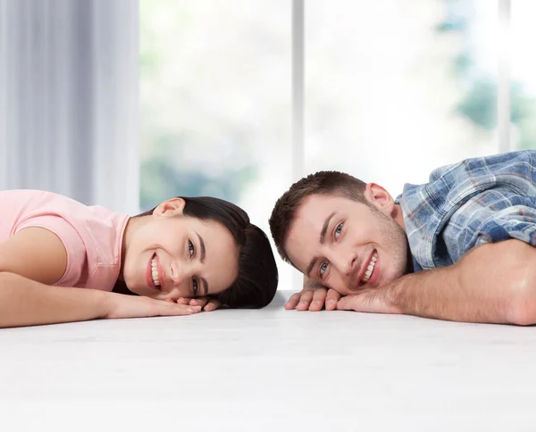 Счастливая молодая пара, лежащая на полу, смотрит друг на друга и мечтает о мебели для новой квартиры. Mock up — стоковое фото
