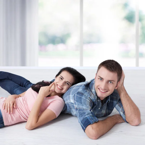 Joyeux jeune couple, couché sur le sol, regardez-vous et rêvez de meubles pour un nouvel appartement. Maquette — Photo