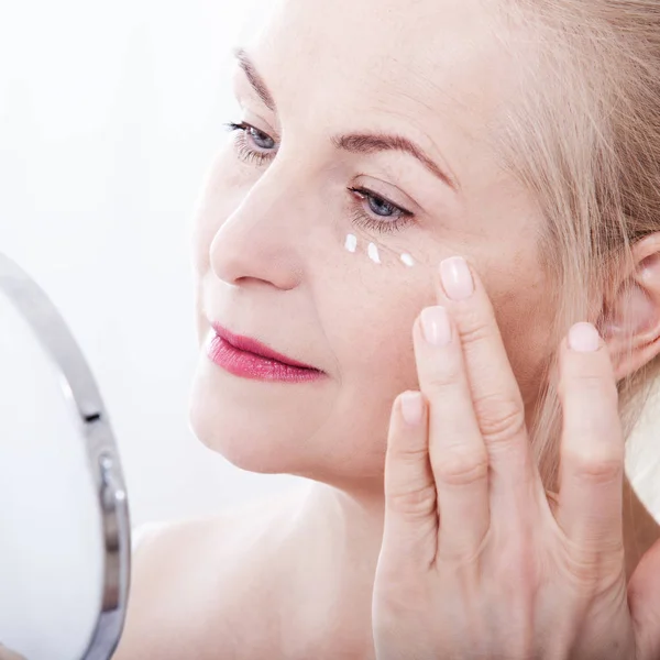 Middle aged woman looking at wrinkles in mirror. Plastic surgery and collagen injections. Makeup. Macro face. Selective focus — Stock Photo, Image