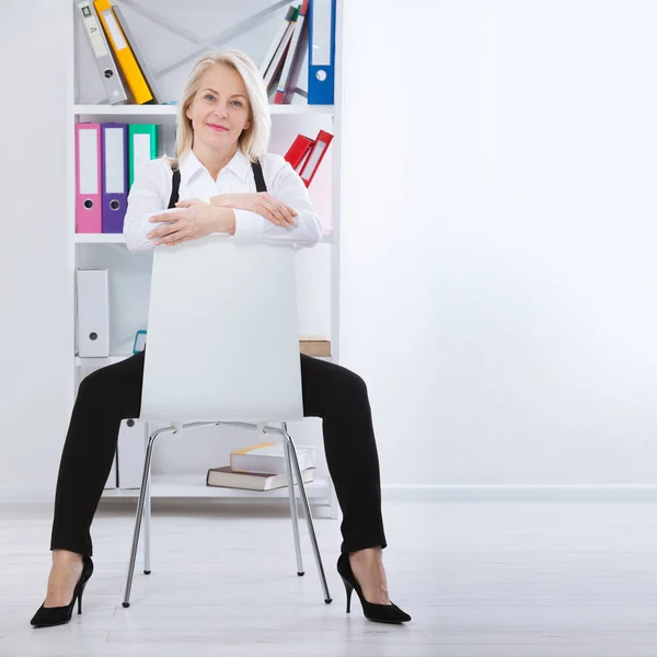 Belle femme blonde d'âge moyen avec un sourire rayonnant assis au bureau regardant la caméra — Photo