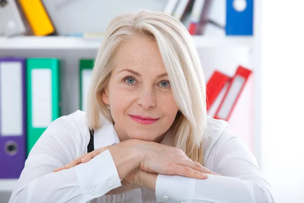 Piękny kobieta w średnim wieku blond z promienny uśmiech siedząc w biurze, patrząc na kamery — Zdjęcie stockowe