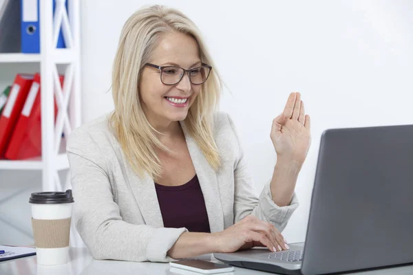 Glad affärskvinna med glasögon fungerar, chating med laptop på kontoret — Stockfoto