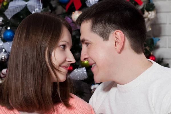 Young couple hugging over Christmas tree at home — Stock Photo, Image