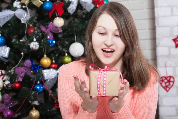 Gelukkig jongedame met geschenken bij de open haard in de buurt van de kerstboom. Nieuwjaar concept. — Stockfoto