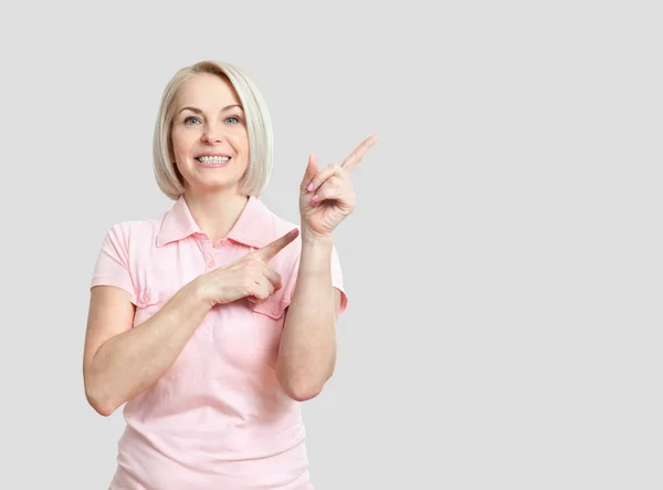 Freundlich lächelnde Frau mittleren Alters zeigt auf Kopierraum isoliert — Stockfoto