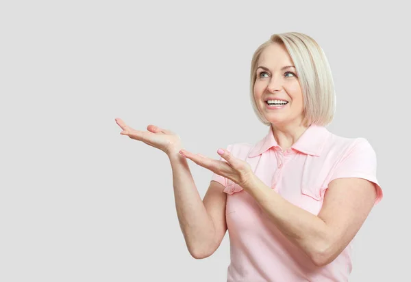Friendly smiling middle aged woman pointing at copyspace isolate — Stock Photo, Image