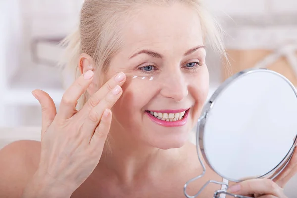 Middle aged woman looking at wrinkles in mirror. Plastic surgery and collagen injections. Makeup. Macro face. Selective focus — Stock Photo, Image