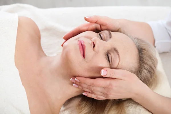 Masaje facial en macro spa. Mujer atractiva con ojos cerrados que cuida la piel. Masaje cara enfoque selectivo . — Foto de Stock