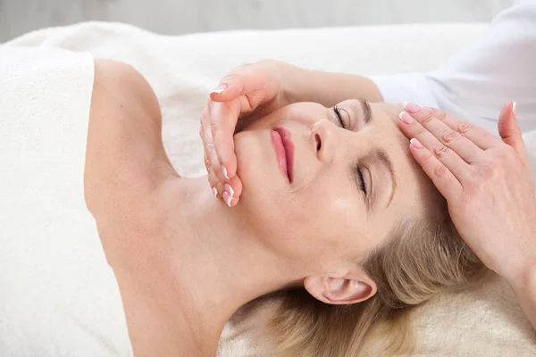 Retrato de mujer hermosa en ambiente spa. mujer de mediana edad haciendo masaje facial en un salón de spa — Foto de Stock