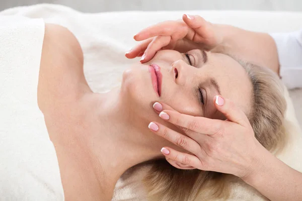 Portrait de belle femme dans un environnement spa. femme d'âge moyen faisant un massage facial dans un salon de spa — Photo