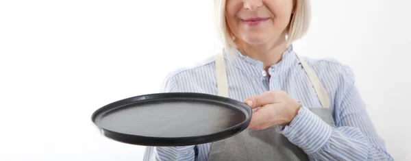 Κουζίνα γυναίκα δίνει άδειο μαύρο πιάτο για τα διαφημιστικά προϊόντα σας απομονώνονται σε λευκό φόντο. Προσομοιωτής για χρήση — Φωτογραφία Αρχείου