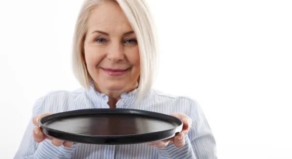 Κουζίνα γυναίκα δίνει άδειο μαύρο πιάτο για τα διαφημιστικά προϊόντα σας απομονώνονται σε λευκό φόντο. Προσομοιωτής για χρήση — Φωτογραφία Αρχείου