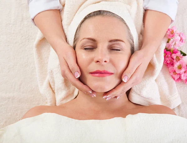 Retrato de mulher bonita em ambiente de spa. mulher de meia idade fazendo massagem facial em um salão de spa — Fotografia de Stock