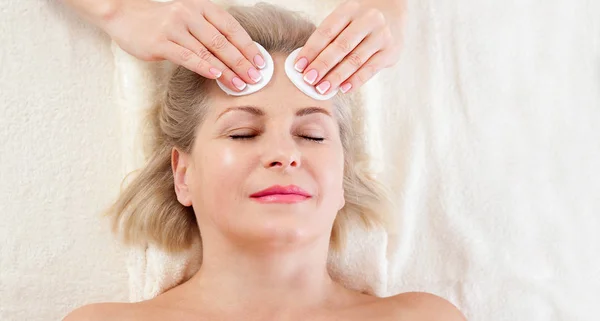 Retrato de mujer hermosa en ambiente spa. mujer de mediana edad haciendo masaje facial en un salón de spa — Foto de Stock