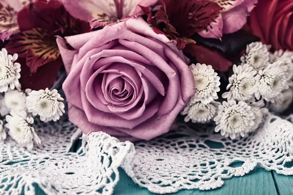 蓝色木桌上的粉红色和白色玫瑰花束,带花边的白色桌布 — 图库照片