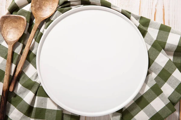 Plato negro o bandeja, o tablero de pizza, con mantel sobre mesa de madera. maqueta vista superior — Foto de Stock