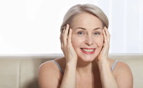 Mujer de 50 años está muy contenta con su rostro bien cuidado. Inyecciones de colágeno de cirugía plástica. Cara de macro. Enfoque selectivo en la cara. Imágenes realistas con sus propias imperfecciones . — Foto de Stock