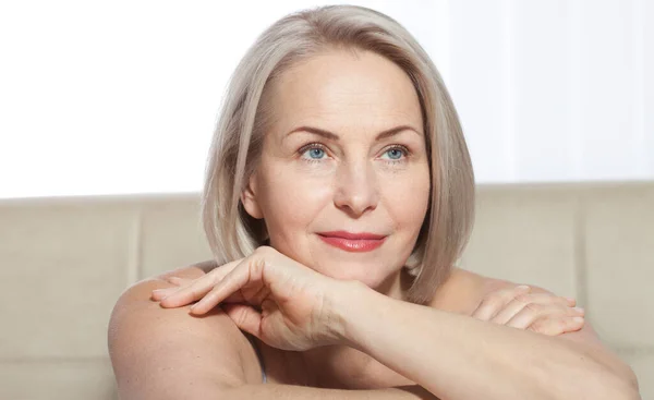 Mujer de 50 años está muy contenta con su rostro bien cuidado. Inyecciones de colágeno de cirugía plástica. Cara de macro. Enfoque selectivo en la cara. Imágenes realistas con sus propias imperfecciones . — Foto de Stock