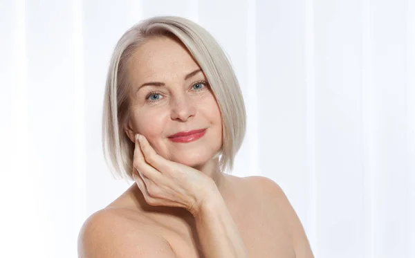 Mujer de 50 años está muy contenta con su rostro bien cuidado. Inyecciones de colágeno de cirugía plástica. Cara de macro. Enfoque selectivo en la cara. Imágenes realistas con sus propias imperfecciones . — Foto de Stock