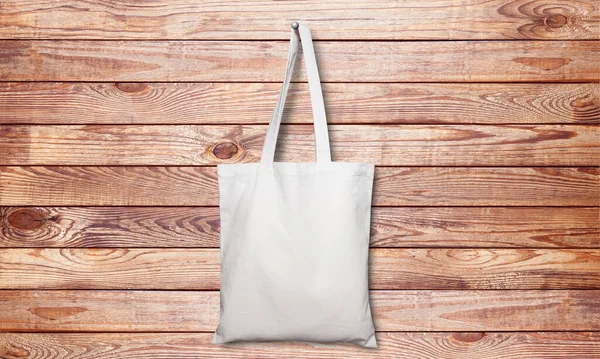 White fabric bag on wooden background. Top view mockup