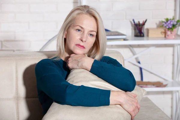 Γυναίκα που υποφέρει από άγχος ή πονοκέφαλο, γκρινιάζει από τον πόνο. Λυπημένη καταθλιπτική γυναίκα στο σπίτι κάθεται στον καναπέ, κοιτάζοντας κάτω και αγγίζοντας το μέτωπό της. — Φωτογραφία Αρχείου