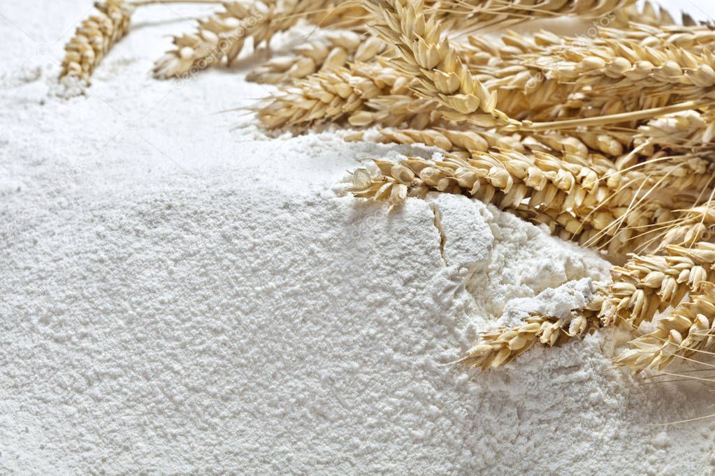 ears of wheat on heap of flour