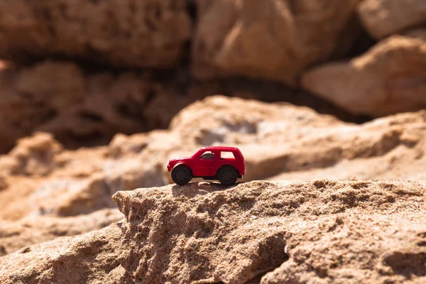 Tiny red car on rocky mountain. Adventure concept.