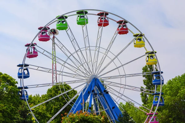 Ferris wiel zonder mensen, tussen groen op de blauwe lucht achtergrond — Stockfoto