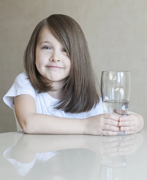きれいな水を飲む幸せの美しい少女。彼女の手で透明なガラスを持って笑顔の赤ちゃんの肖像画 — ストック写真