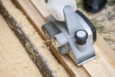 Elektrikli planya açık ile çalışan bir adamın elini. Talaş enkaz makineden atılır. Sağ el ile işlemek. Malzeme işleme. İş takım. Ağaç işleme ve işçilik kavramı