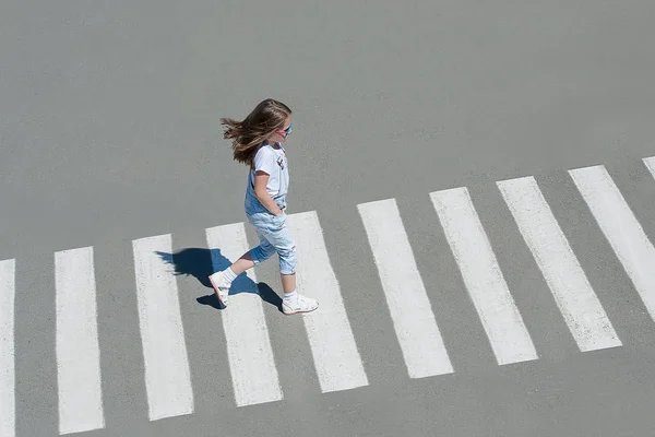 No verão na rua no pedestre que cruza a menina de criança com a roupa de moda cruza a estrada. Da vista de cima. Sombra na travessia de zebra — Fotografia de Stock