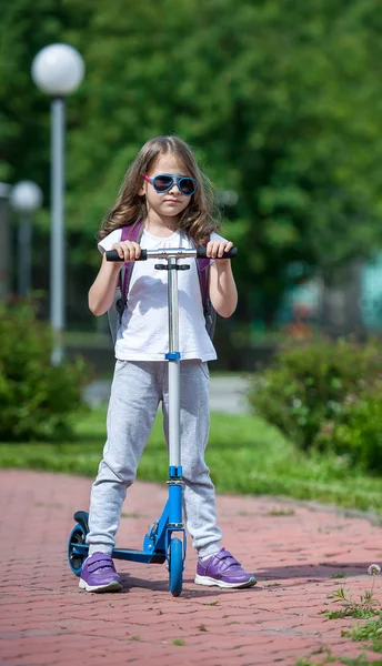 Scooter infantil. Niño en tablero de patadas de colores. Diversión activa al aire libre para niños. Deportes de verano para niños en edad preescolar. Niña feliz en el parque de primavera. El concepto de un estilo de vida saludable —  Fotos de Stock