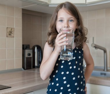 Küçük çocuk evde temiz su içiyor, yakın. Uzun saçlı Kafkas sevimli kız elinde bir su camı tutuyor. Kendi sağlığına bakıyorum. Sağlıklı yaşam konsepti, iyi alışkanlık