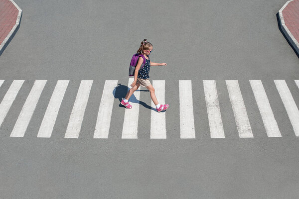 Schoolgirl crossing road on way to school. Zebra traffic walk 