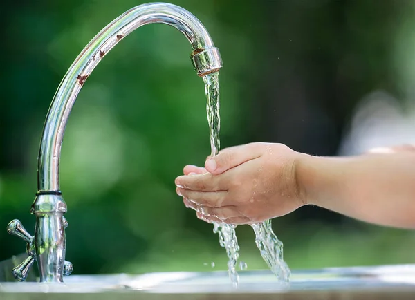 Hands open for drinking tap water. Pouring fresh healthy drink. Good habit. Right choice. Child washes his hand under the faucet in the garden. Environment and health care concept. World Water Day