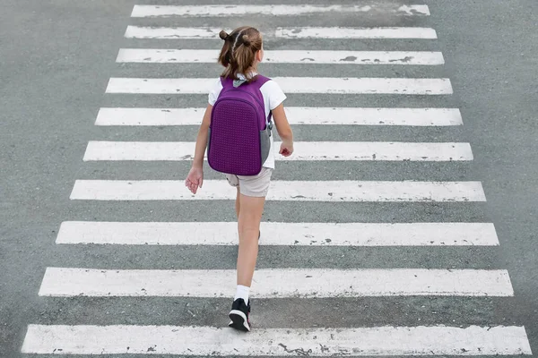 Liseli kız okula giderken karşıdan karşıya geçiyor. Zebra trafiği şehrin öbür ucunda. Yaya geçidinden geçen yayalar. Sırt çantasıyla gezen şık bir genç kız. Aktif çocuk. Üst görünüm