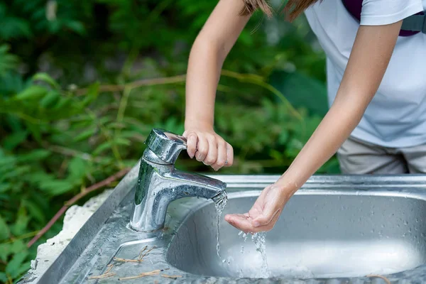 Baby try to turn off water faucet but water still leak. A child\'s hand turning off the tap. Save water. World Water Monitoring Day. Environment and health care concept. Natural green background