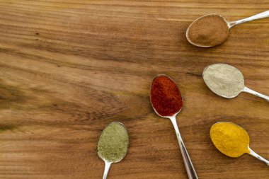 Kaşıklar üzerine düzenlenmiş çeşitli renkli baharatlar 