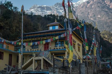 Budist dua bayraklarıyla sarı Budist manastırı, Himalaya dağlarının altında Annapurna pisti boyunca