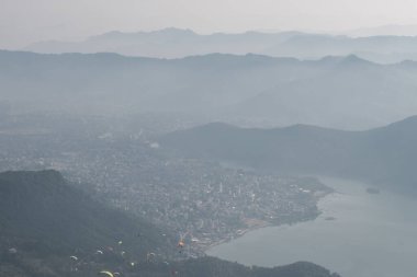 Pokhara şehri, göl ve yuvarlanan tepeler üzerindeki yamaç paraşütçüleri, Sarangkot tepesinden Nepal, Aralık 2019