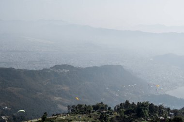 Pokhara şehri, göl ve yuvarlanan tepeler üzerindeki yamaç paraşütçüleri, Sarangkot tepesinden Nepal, Aralık 2019