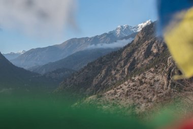 Yukarı Pisang 'ı çevreleyen dağlar renkli Budist dua bayrakları boyunca, Marshyangdi nehri üzerinde, Annapurna pisti, Nepal