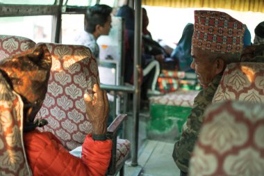 Geleneksel giysiler içinde iki yaşlı nepalli adam Ngadi, Annapurna pistine giderken yerel otobüste tartışıyorlar.