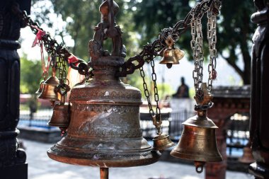 Pokhara, Nepal 'deki küçük bir Hindu tapınağında zincirlerle birbirine bağlanmış birkaç büyük ve küçük çan.