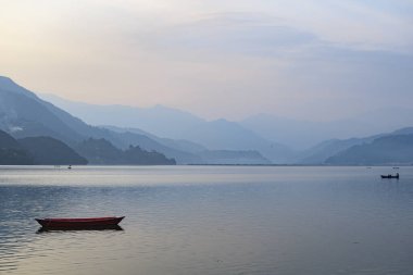 Pokhara, Nepal 'deki Phewa Gölü' nde çevresindeki dağlarla dolu renkli bir tekneye bakın. Güneşli bir gün. Rahatlama ve sükunet, huzur ve sessizlik..
